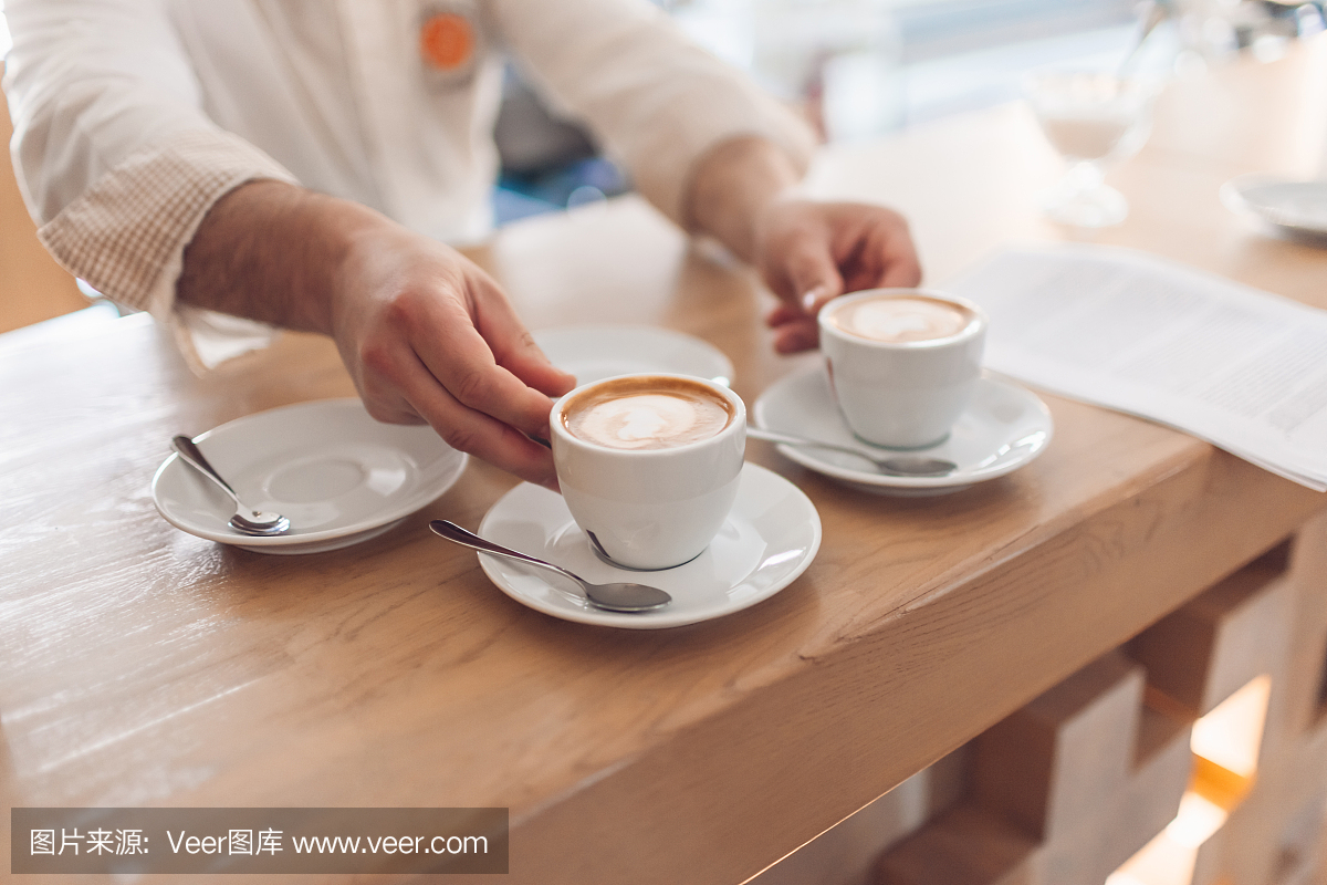 咖啡师每天早上在咖啡馆里提供两杯新鲜的卡布奇诺